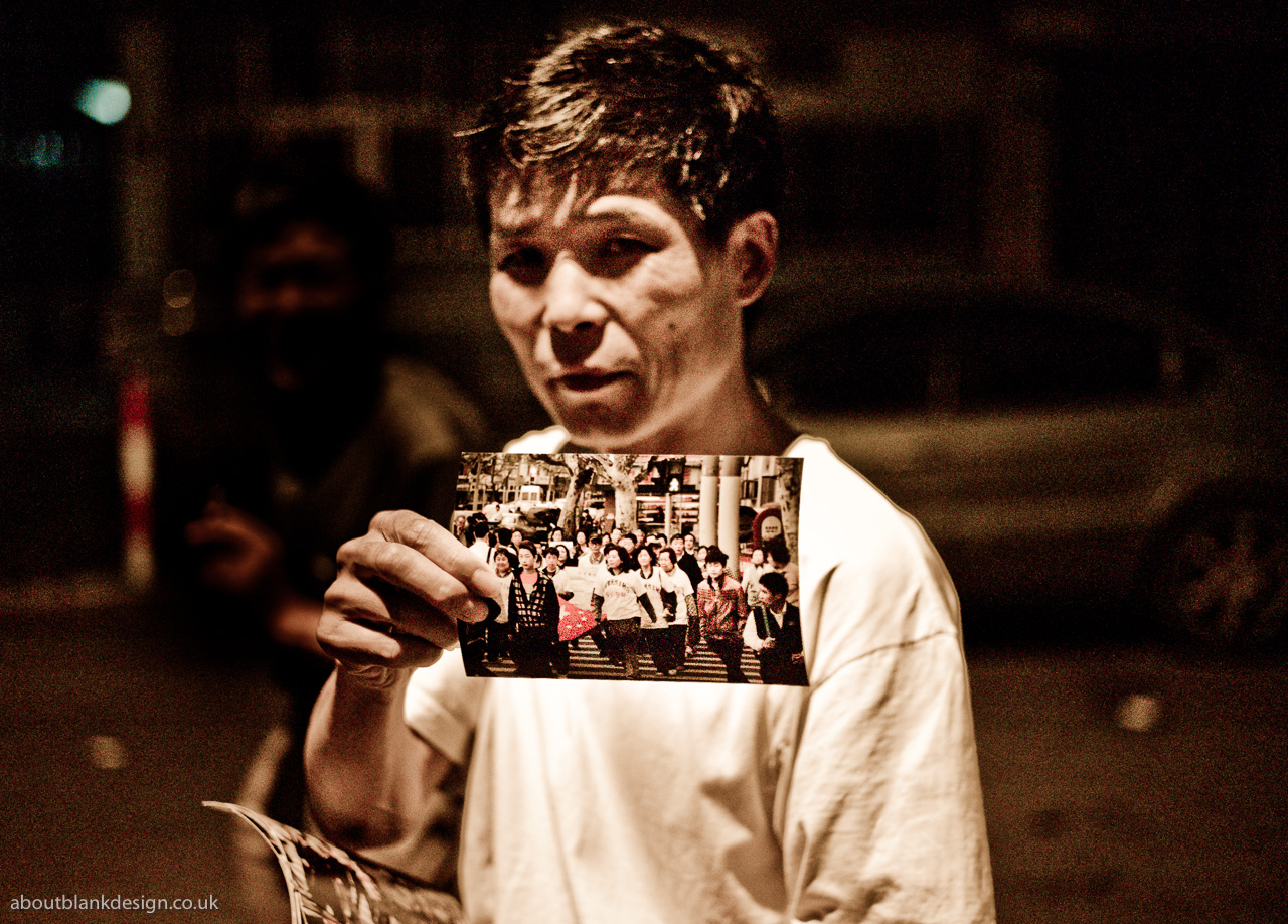 #20 Xiaonanment resident showing photo of recent protest marches, Xiaonanmen, Shanghai, China, July 2012