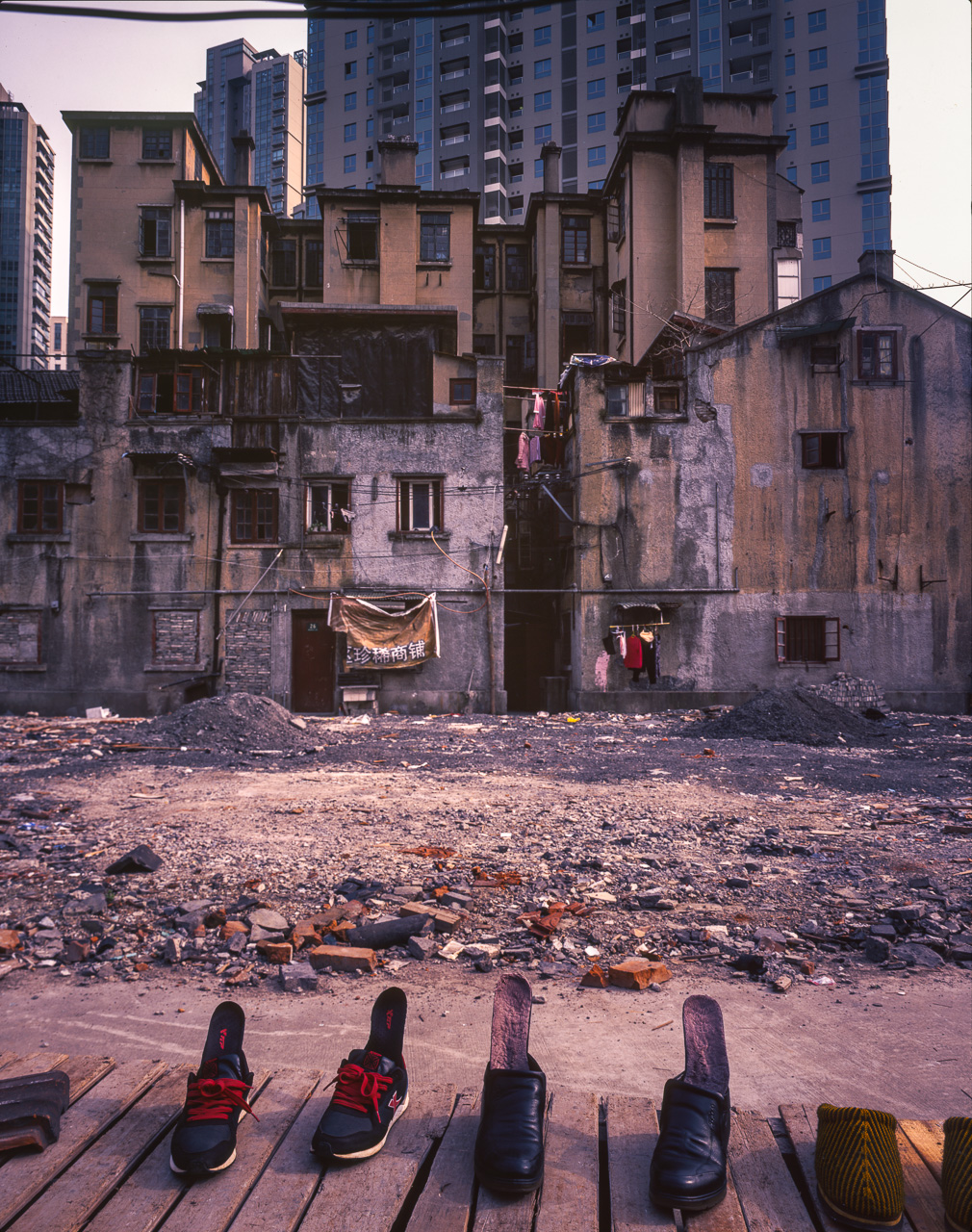 #38 A bunch of shoes drying infront of dilapitated houses. The clothes hanging in the middle strongly suggest people still live there.